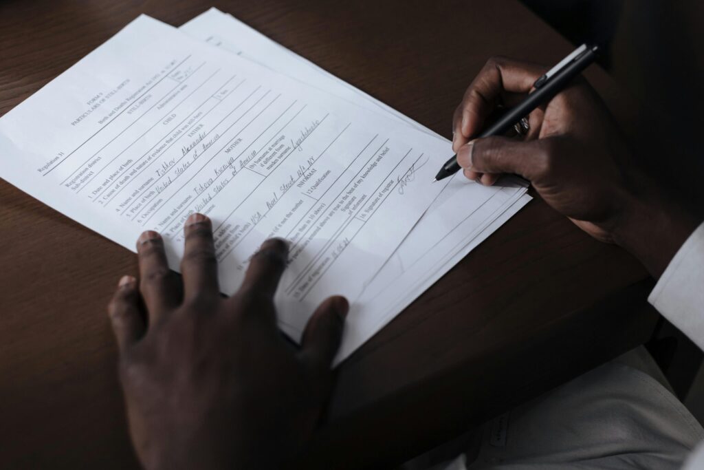 pexels-photo-9870227-9870227 A detailed view of a man signing official documents with a pen at a table.